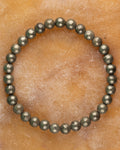 Pulsera de Pirita de 6 mm, pieza completa en círculo sobre superficie ambar