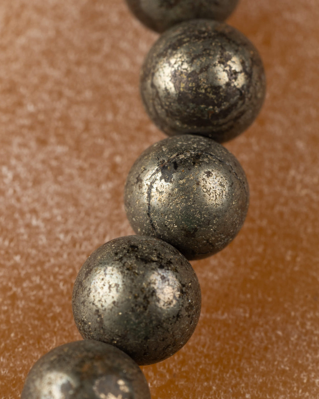 Detalle macro vertical de cuentas de Pirita con superficie metalica moteada