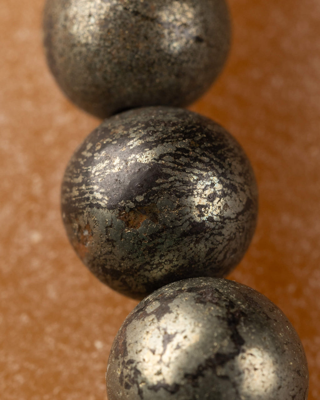 Detalle macro de cuentas de Pirita, textura oscura con vetas doradas brillantes
