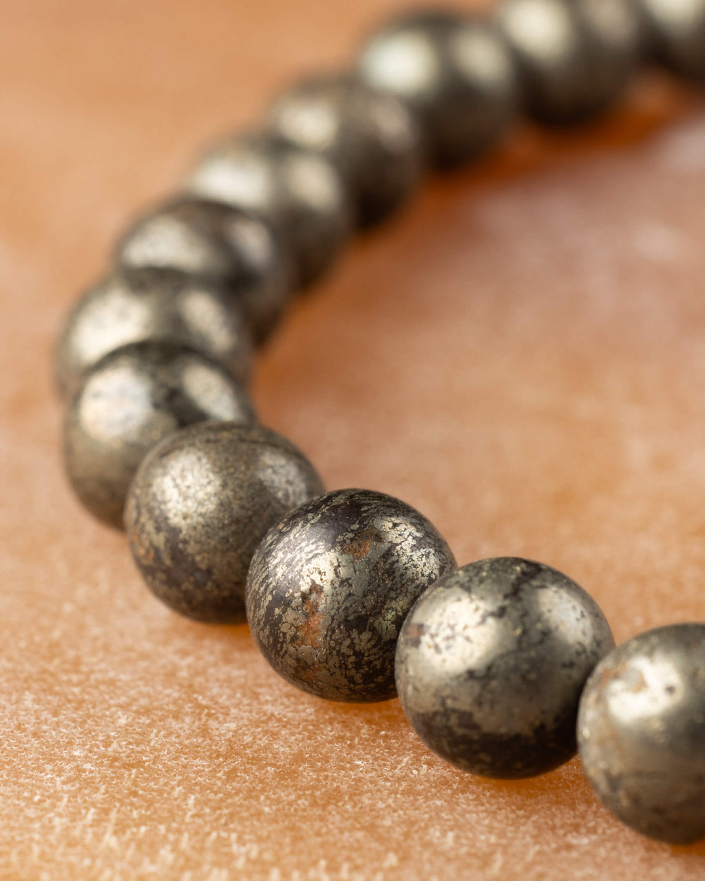 Pulsera de Pirita en perspectiva, curva de cuentas sobre superficie ambar