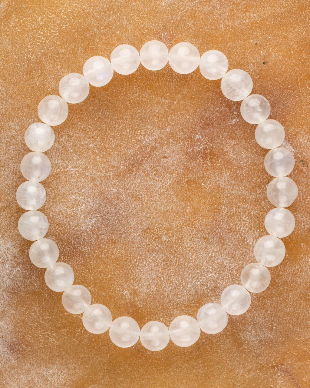 Pulsera de la Piedra Luna de 7 mm, pieza completa en círculo sobre superficie color miel