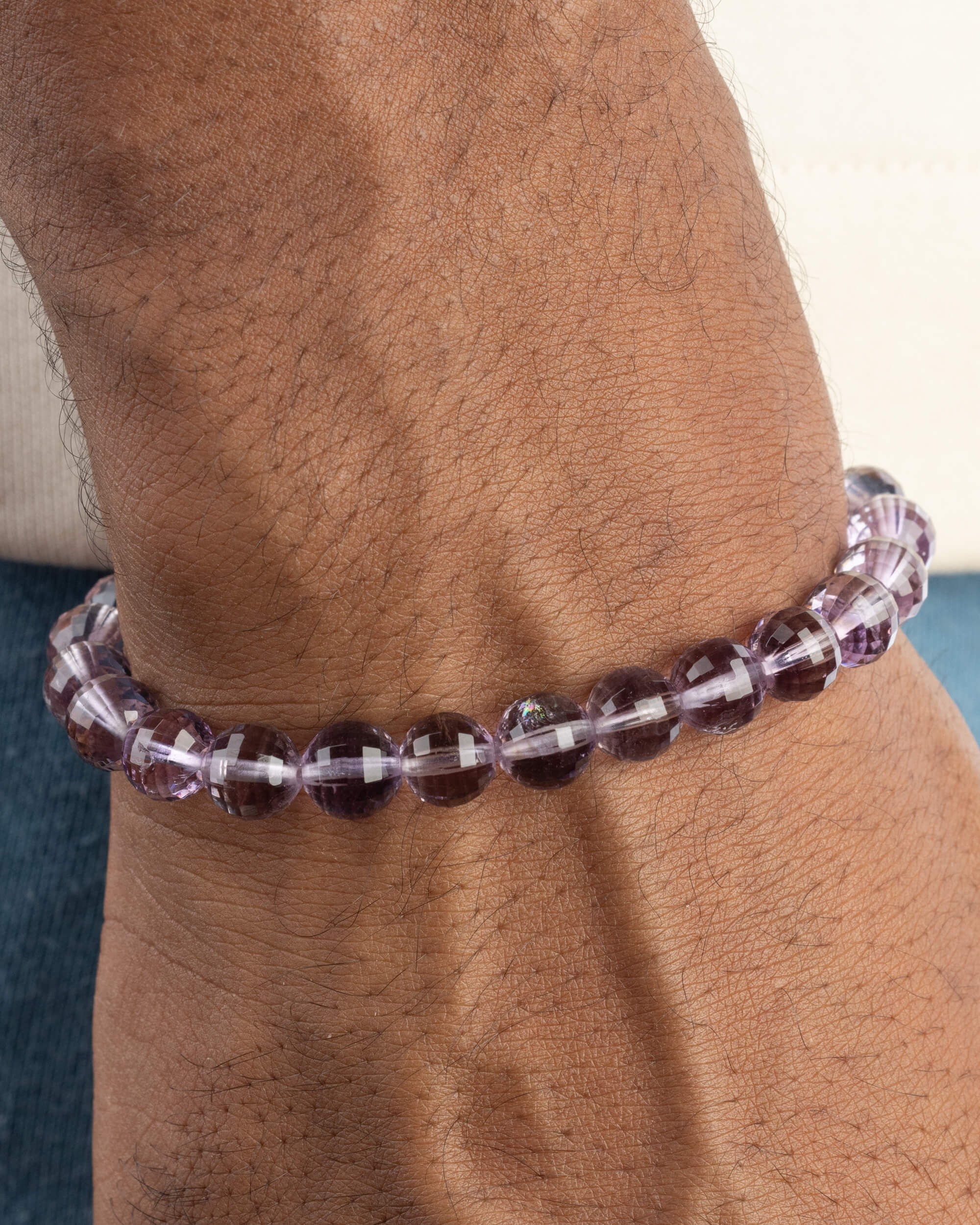 Pulsera de Amatista facetada puesta en la muñeca, con mezclilla azul al fondo
