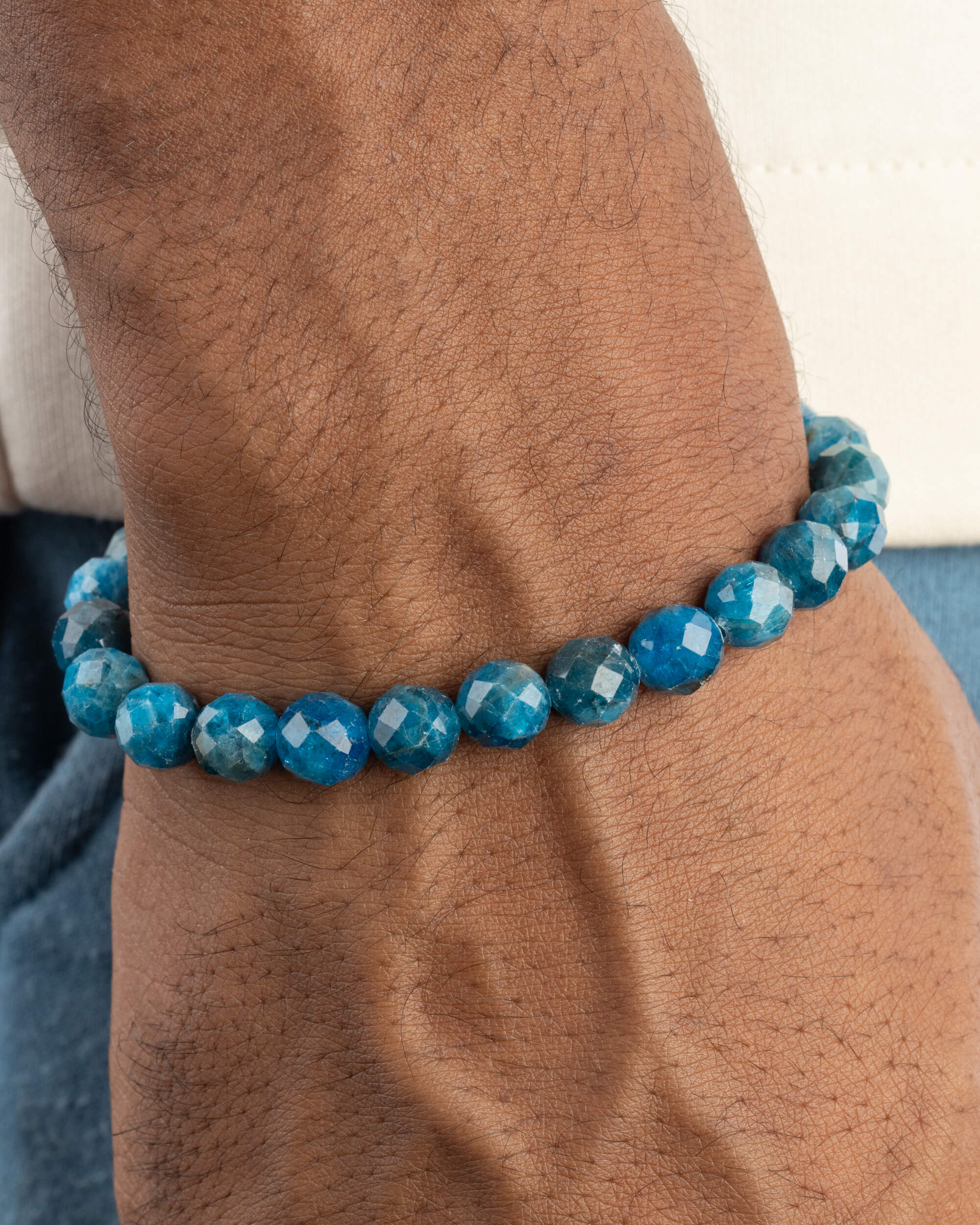 Pulsera de Apatita Azul facetada puesta en la muñeca, con manga clara al fondo