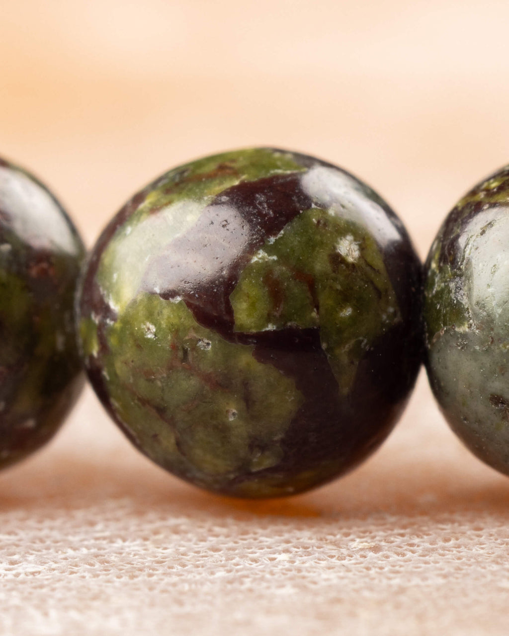 Detalle macro de una cuenta de Jaspe Sangre de Dragón con vetas verdes y oscuras