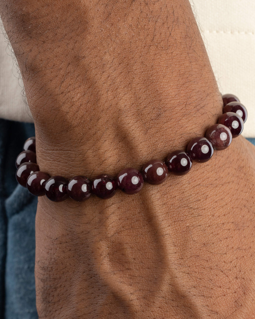 Pulsera de Granate Estrella puesta en la muñeca, con las cuentas de tono vino profundo