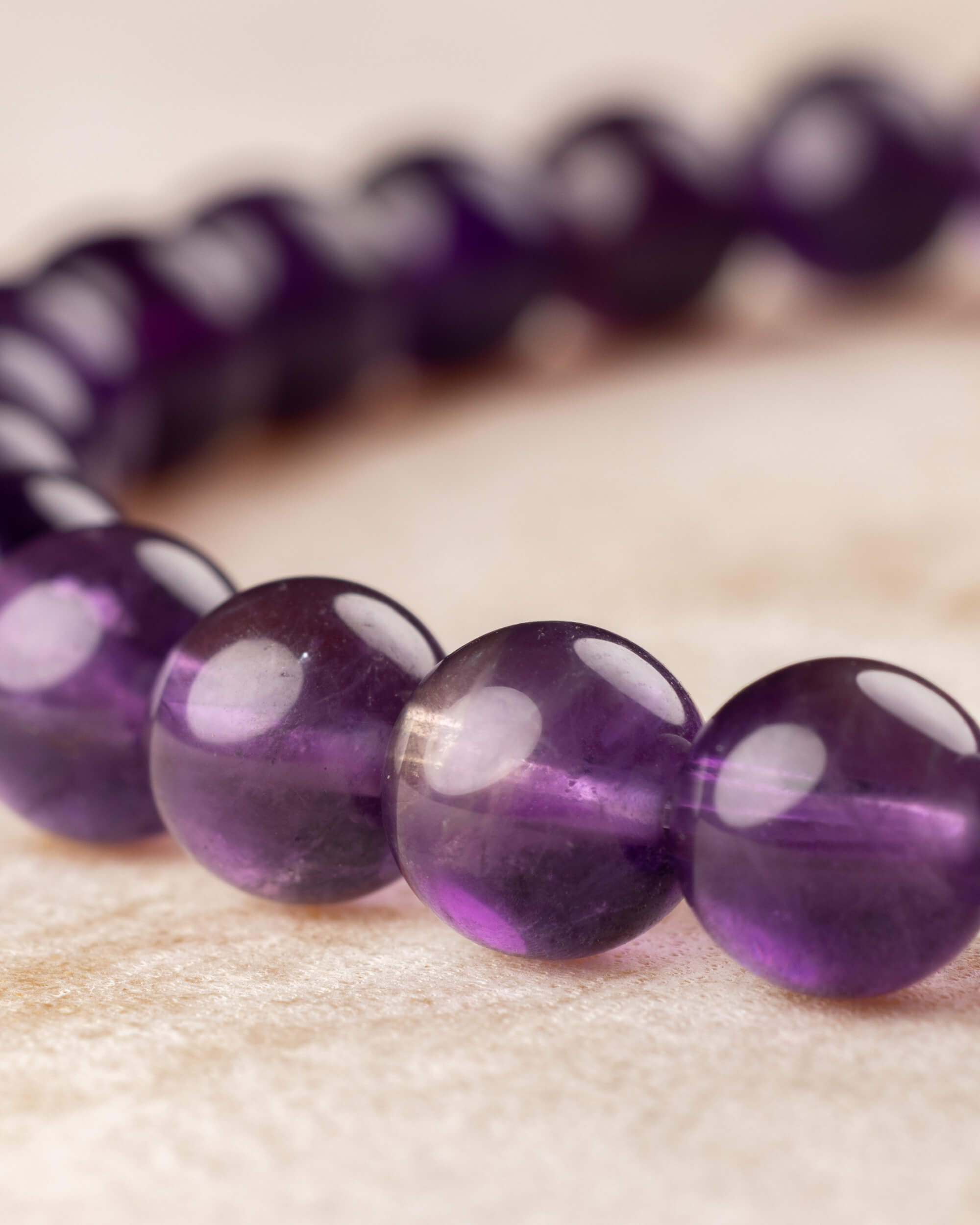 Pulsera de Amatista curvada, cuentas en primer plano con fondo desenfocado