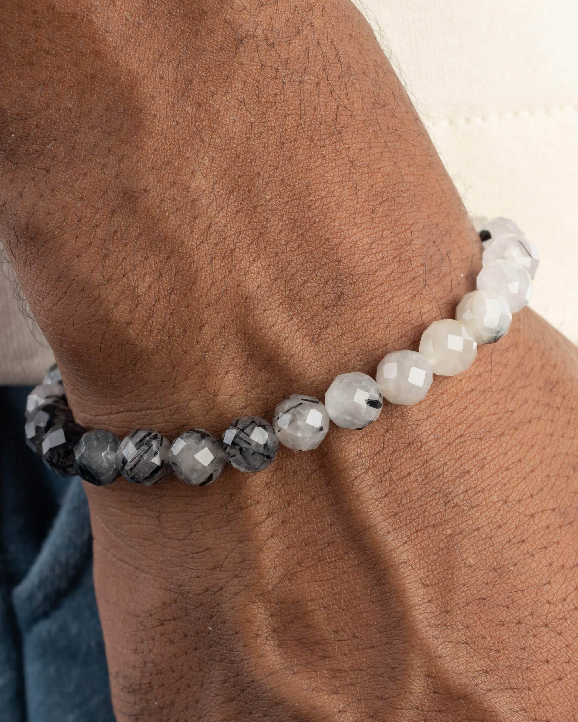 Pulsera de Cuarzo Turmalinado facetada puesta en la muñeca, con degradado de claro a oscuro