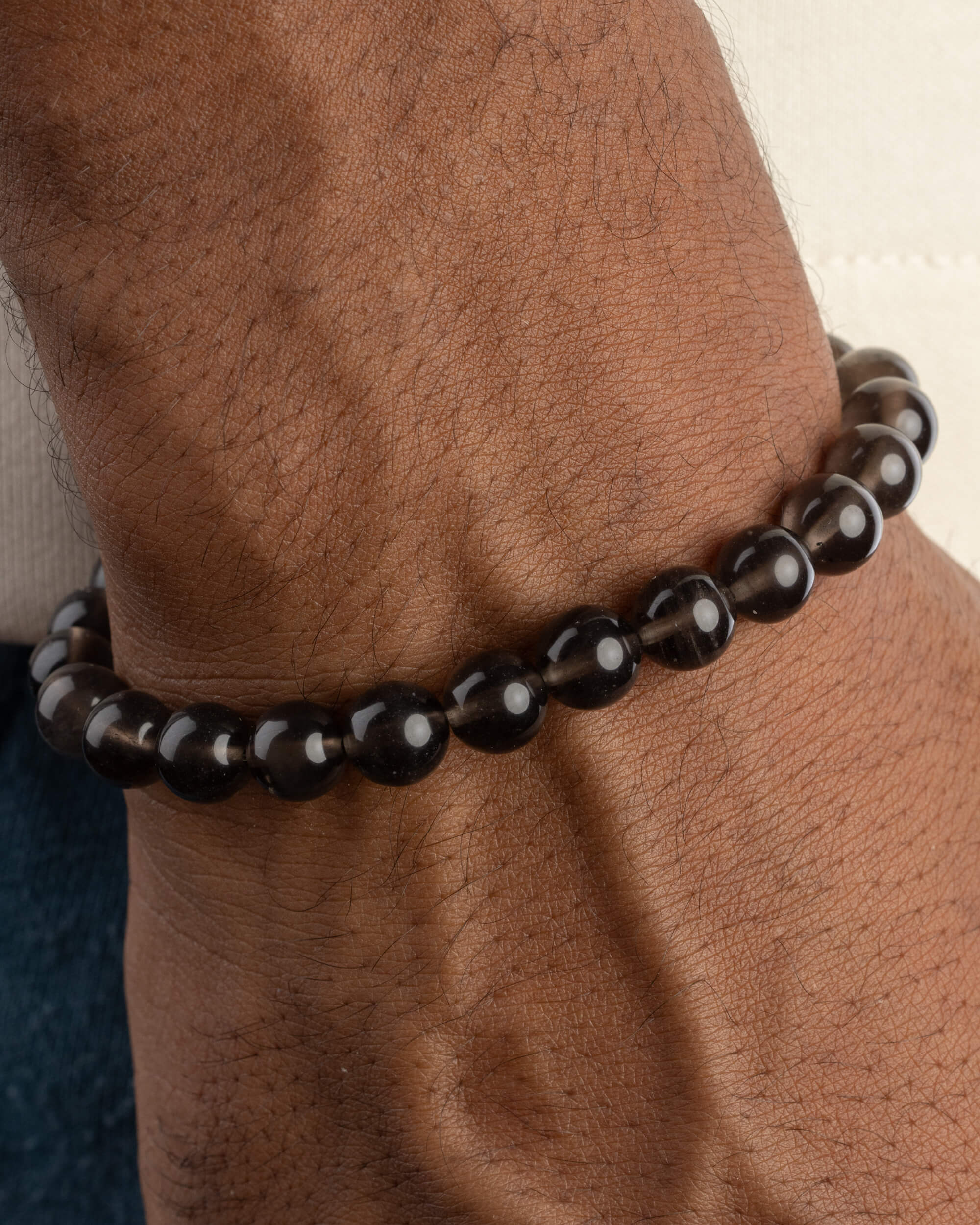 Pulsera de Saffordita puesta en la muñeca, con las cuentas de tono oscuro traslucido