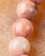 Detalle macro de cuentas de Rodonita Rosa con manchas blancas y motas oscuras