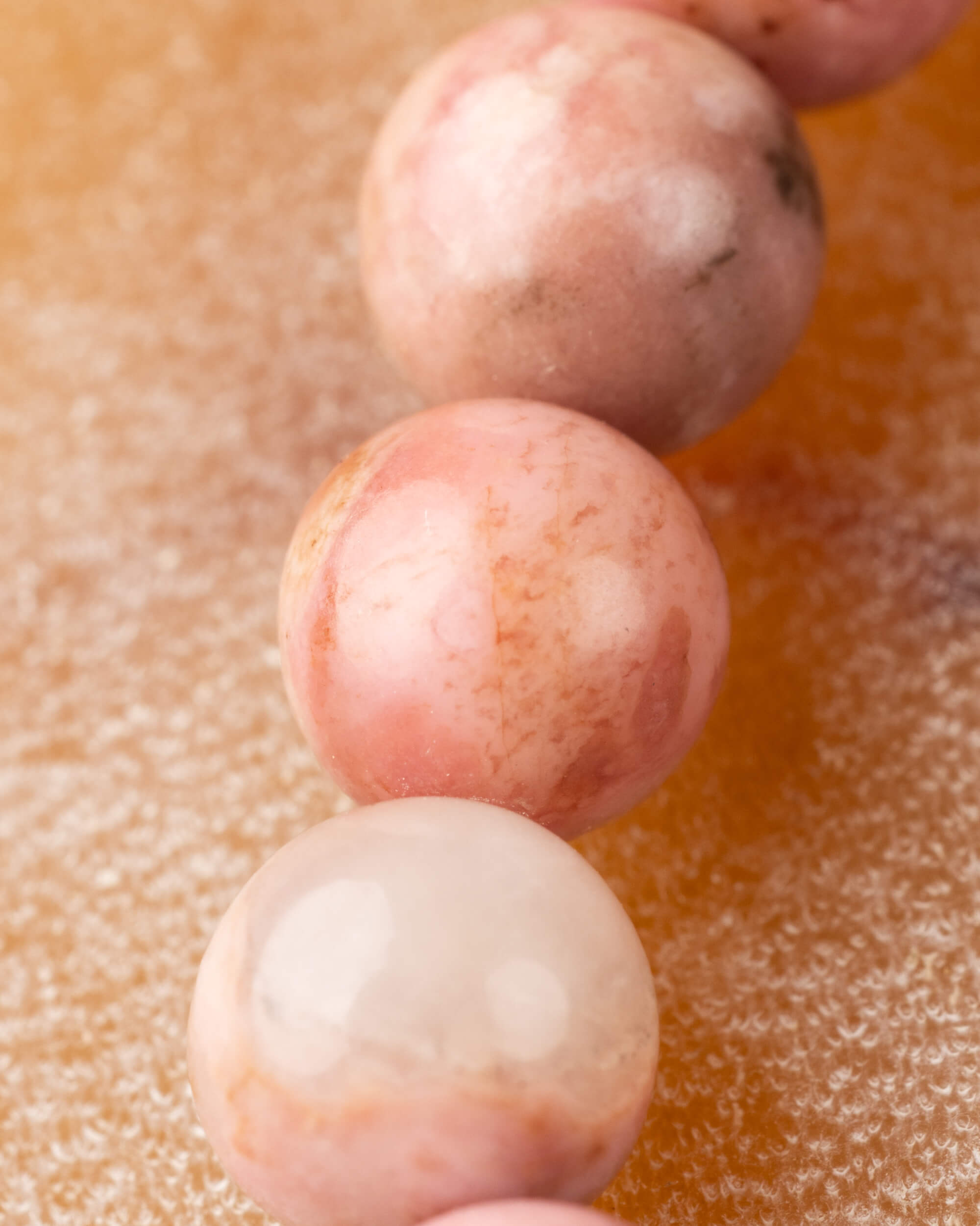Detalle macro de cuentas de Rodonita Rosa con manchas blancas y motas oscuras