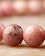 Detalle macro de cuentas de Rodonita Rosa con manchas negras naturales