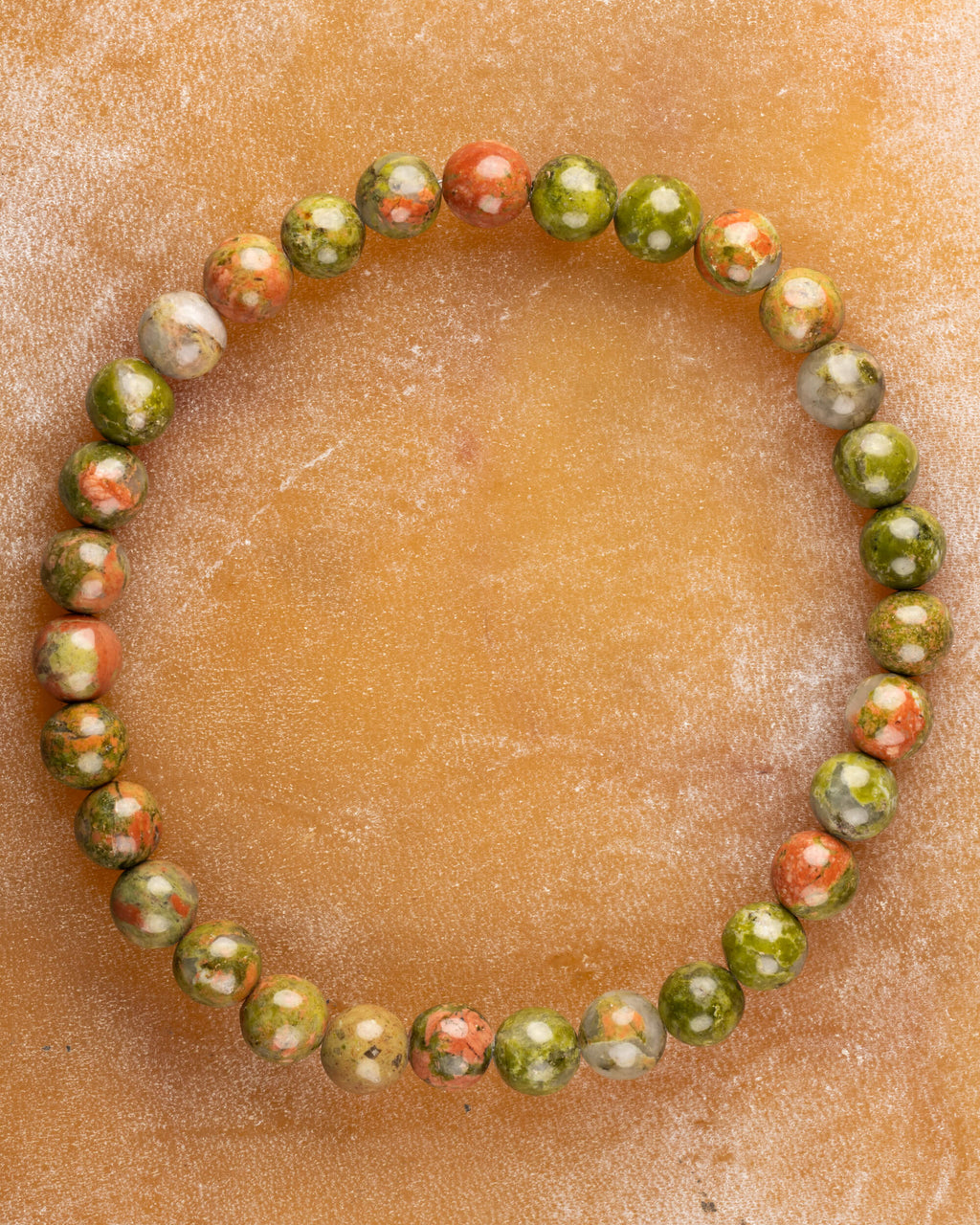 Pulsera de Jaspe Unakita de 6 mm, pieza completa sobre superficie de piedra clara