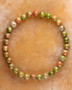 Pulsera de Jaspe Unakita de 6 mm, pieza completa sobre superficie de piedra clara