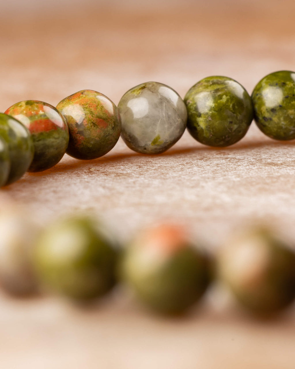 Macro de las cuentas de Jaspe Unakita, manchas rosadas y verdes sobre piedra