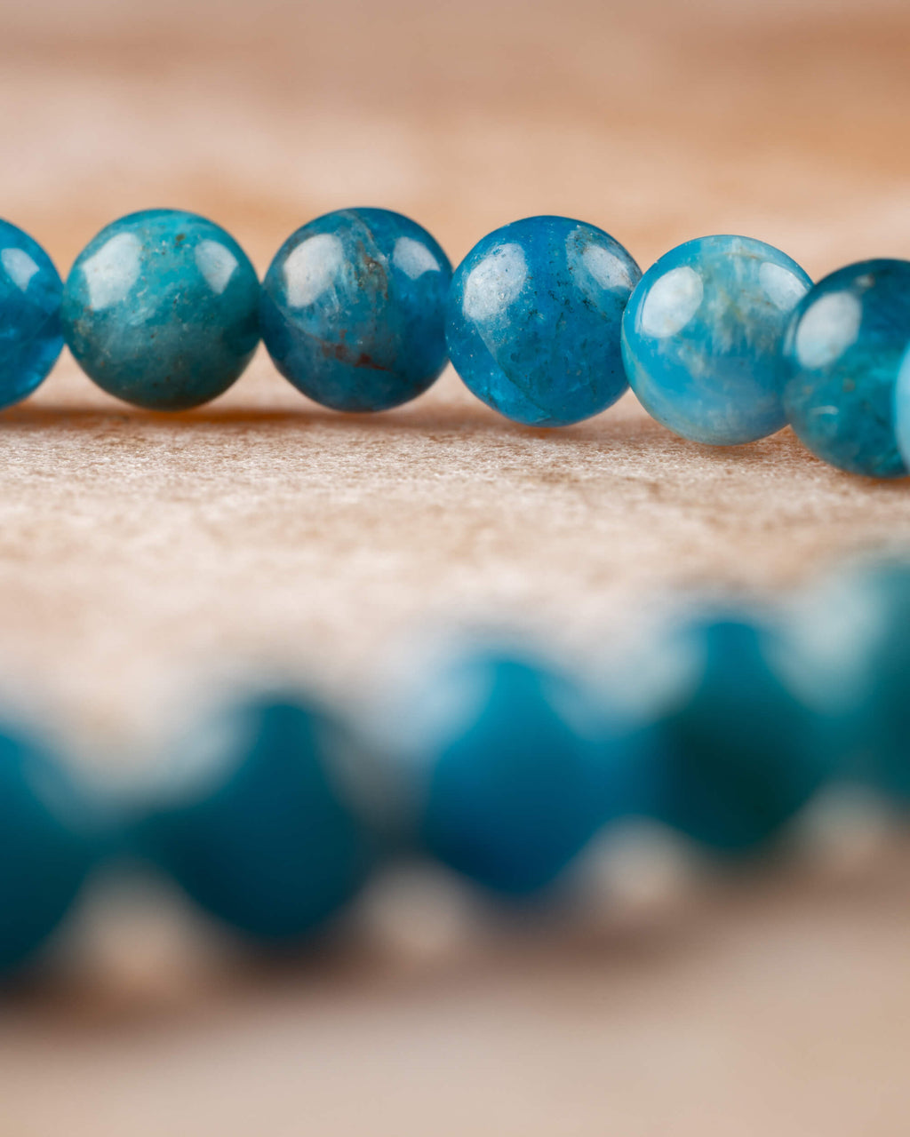 Cuentas de Apatita Azul vistas en fila con curva de la pulsera de fondo