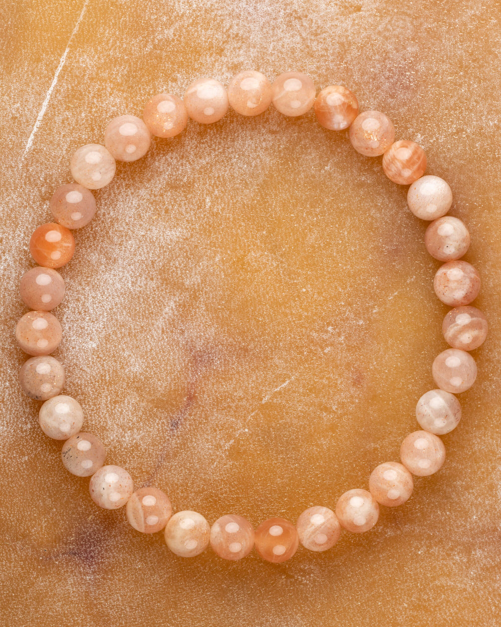 Pulsera de Piedra Sol Naranja de 6 mm, pieza completa sobre superficie color miel