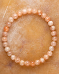 Pulsera de Piedra Sol Naranja de 6 mm, pieza completa sobre superficie color miel