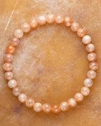 Pulsera de Piedra Sol Naranja de 6 mm, pieza completa sobre superficie color miel