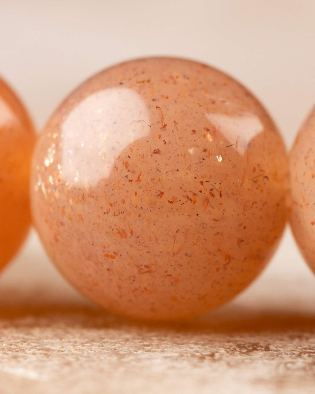 Detalle macro de una cuenta de Piedra Sol Naranja con destellos dorados