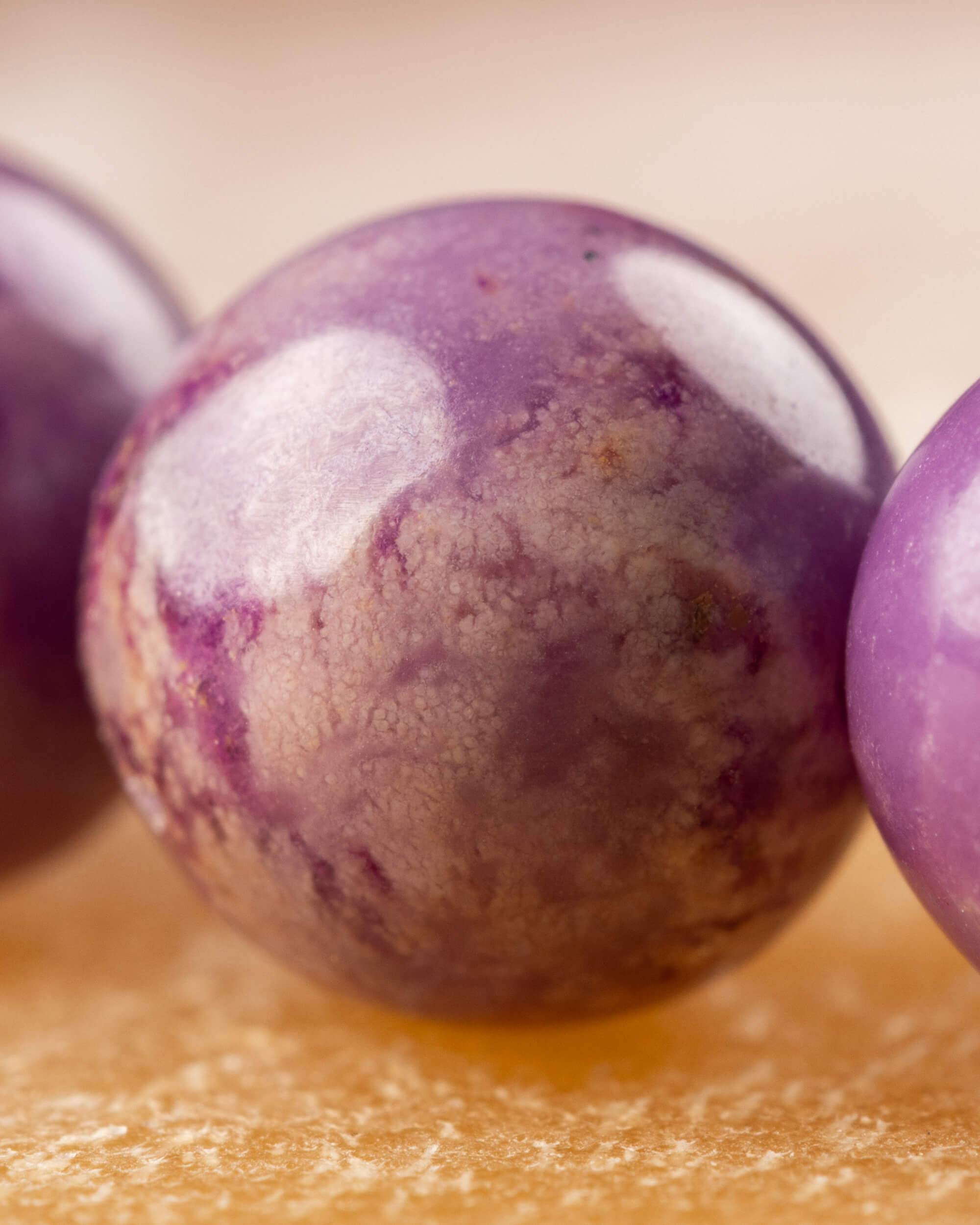 Detalle macro de una cuenta de Fosfosiderita con textura moteada morada y beige