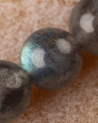 Primer plano de una cuenta de Labradorita con reflejo azul en su superficie