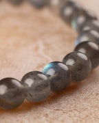 Pulsera de Labradorita curvada en primer plano con destello dorado en una cuenta