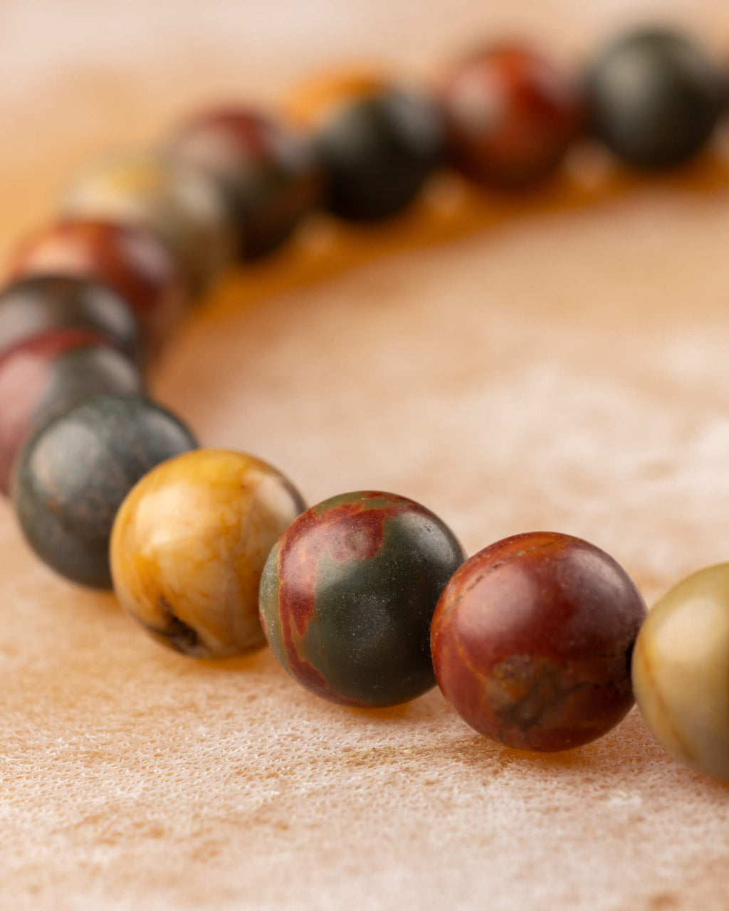 Pulsera de Jaspe Picasso en curva, mostrando la variedad de tonos de sus cuentas