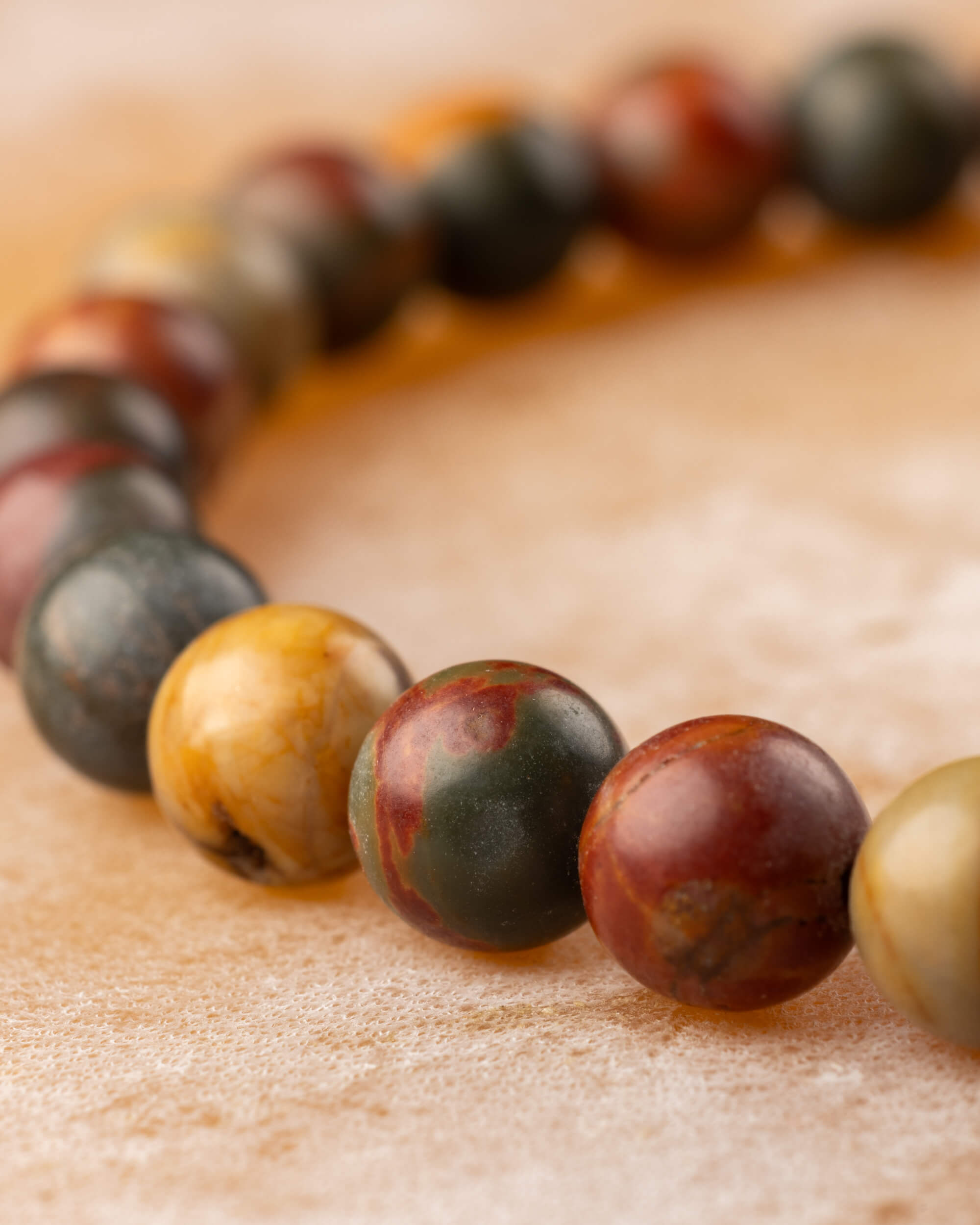 Pulsera de Jaspe Picasso en curva, mostrando la variedad de tonos de sus cuentas