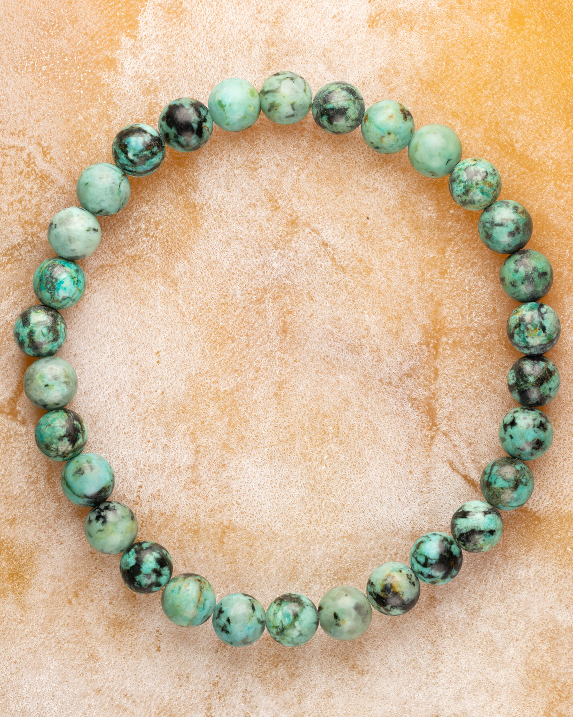 Pulsera de Turquesa Africana de 6 mm, pieza completa sobre superficie dorada