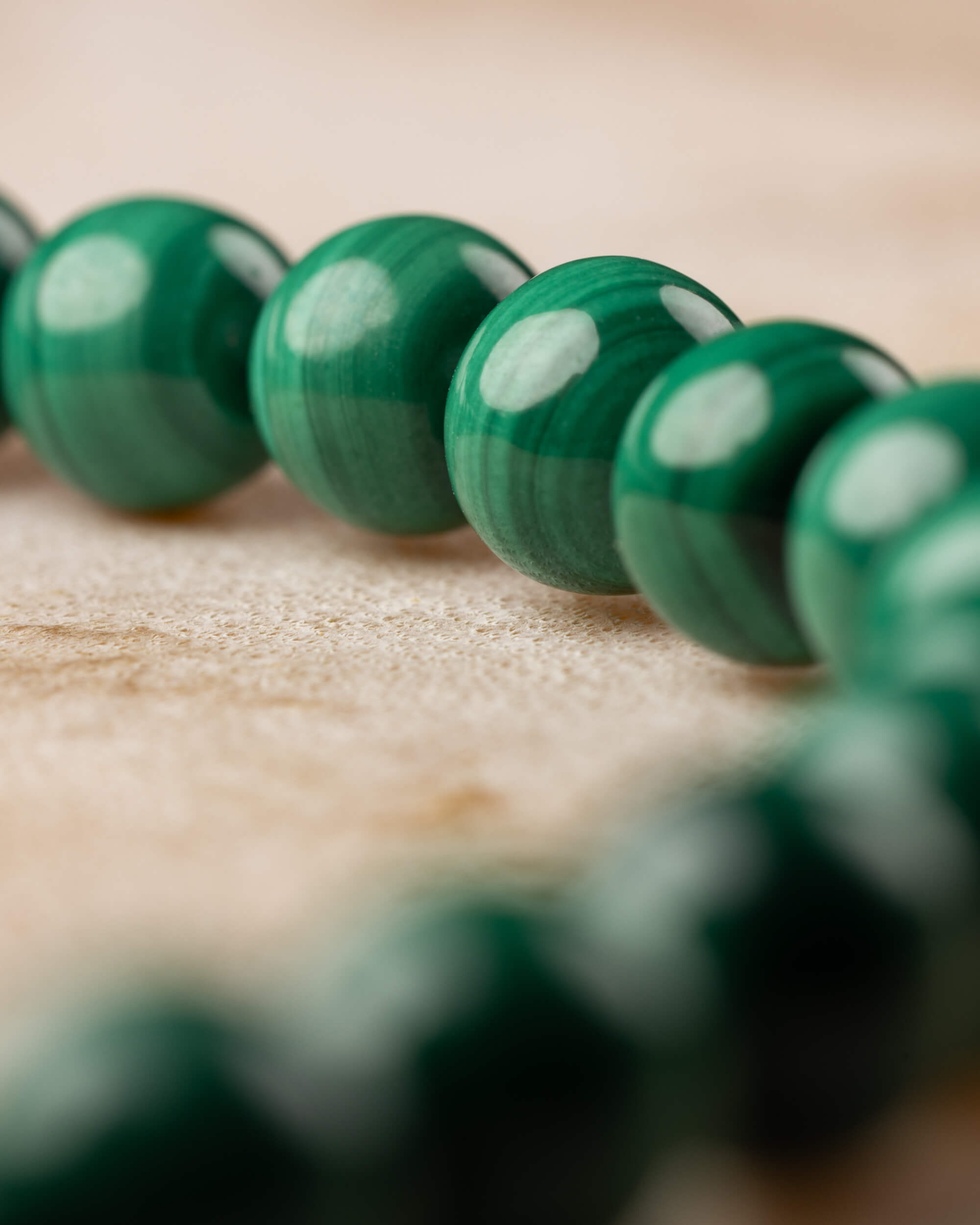 Pulsera de Malaquita en ángulo bajo, cuentas verdes en primer plano y fondo difuso