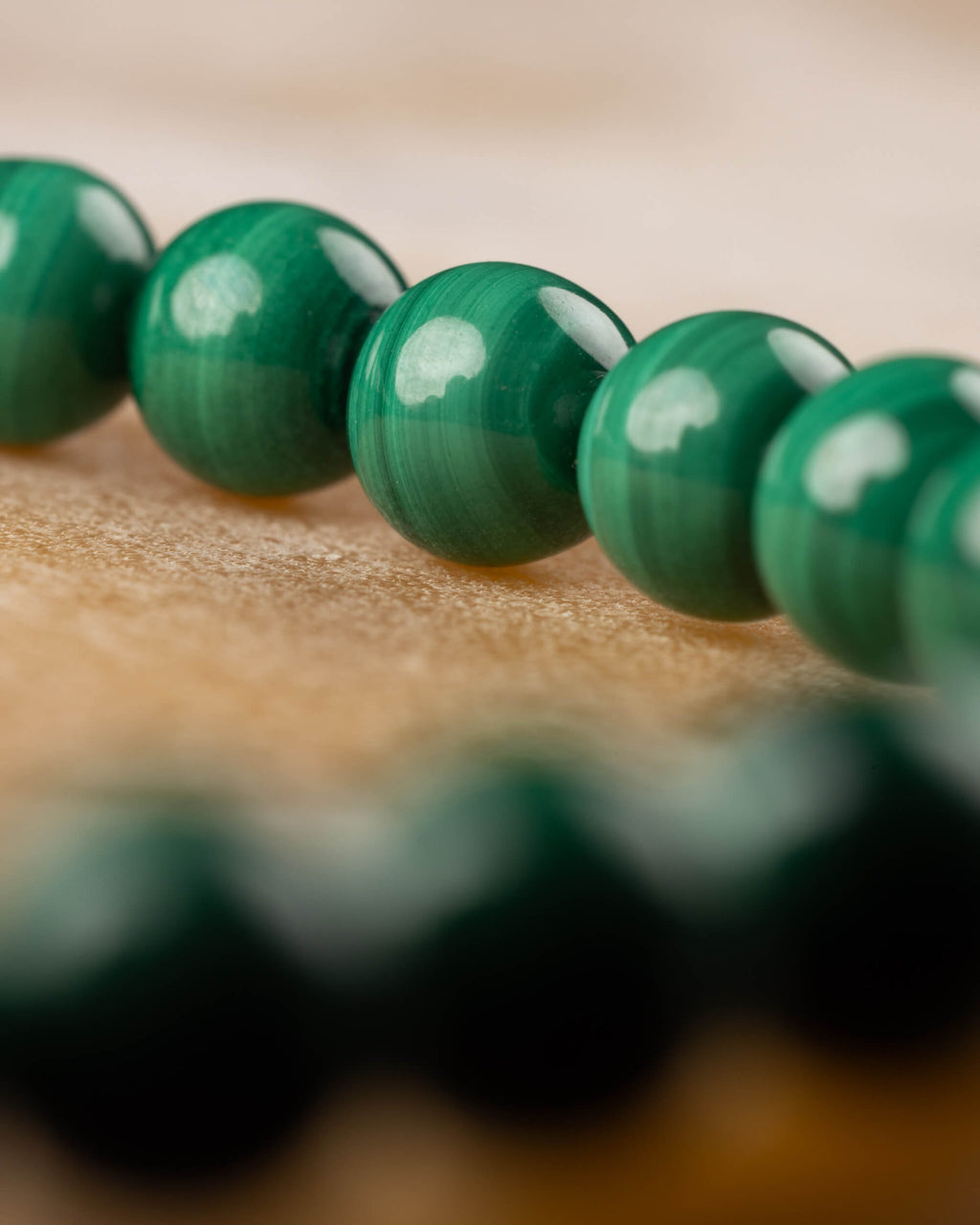 Pulsera de Malaquita en ángulo bajo, cuentas verdes brillantes sobre madera clara