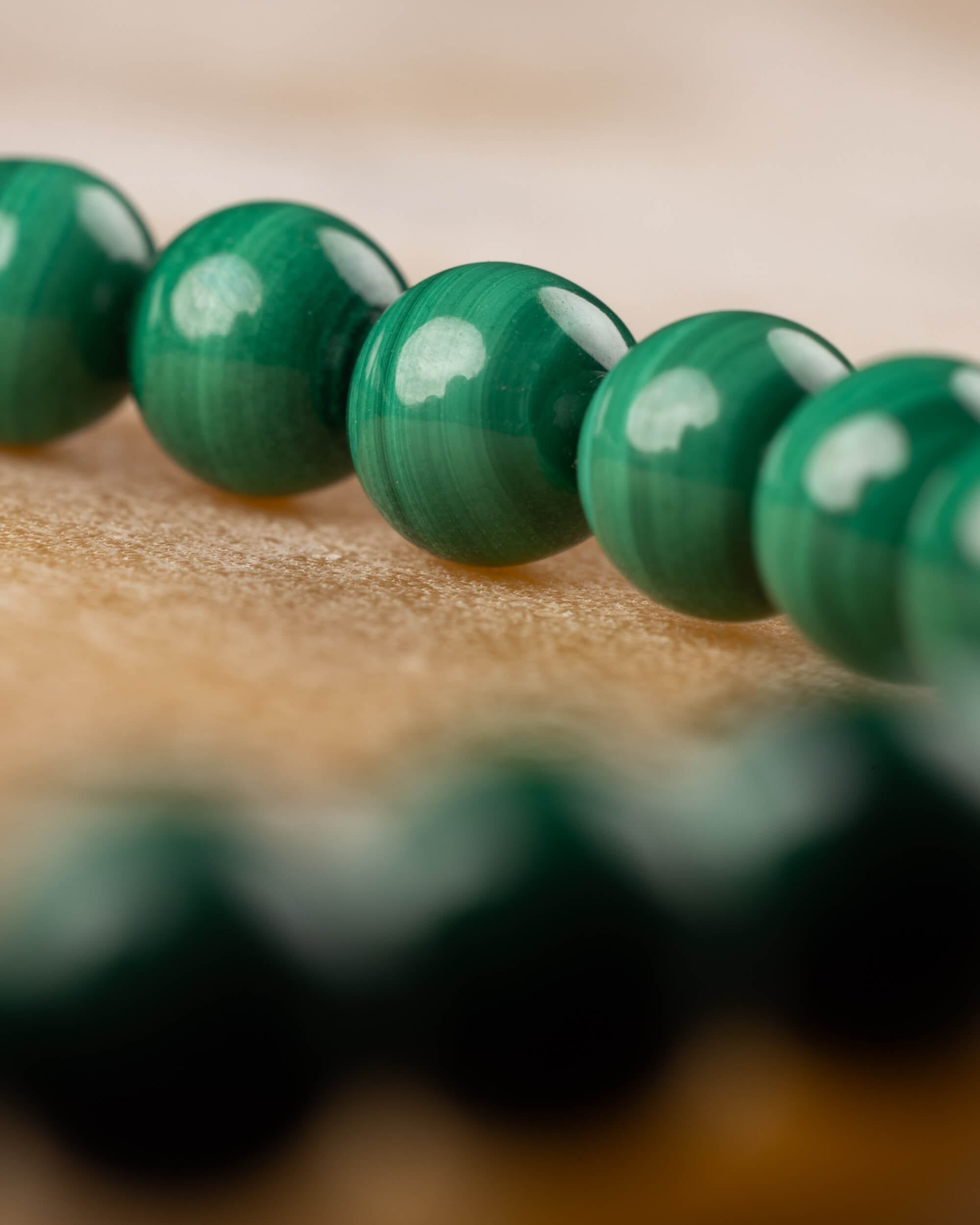 Pulsera de Malaquita en ángulo bajo, cuentas verdes brillantes sobre madera clara