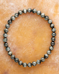 Pulsera de Ojo de Halcon de 6 mm, pieza completa sobre superficie color miel