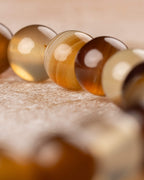 Detalle macro de cuentas doradas y rayadas de Ágata Café en la curva de la pulsera