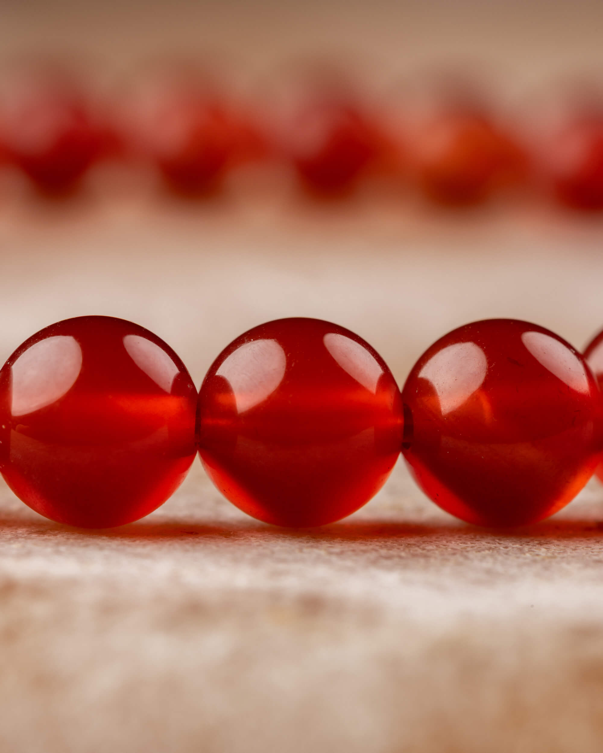 Vista en ángulo de las cuentas rojas de la pulsera de Cornalina sobre tela clara