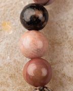 Macro vertical de tres cuentas de Rodonita encaje negro, tonos rosa y café con vetas negras