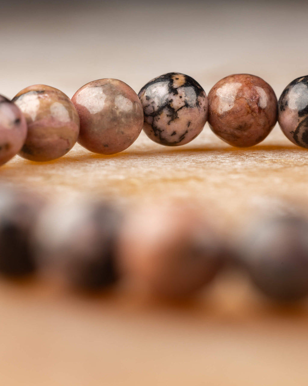 Perspectiva de la pulsera de Rodonita encaje negro sobre superficie clara, doble vuelta visible