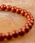 Pulsera de Jaspe Rojo curvada en ángulo diagonal sobre superficie clara