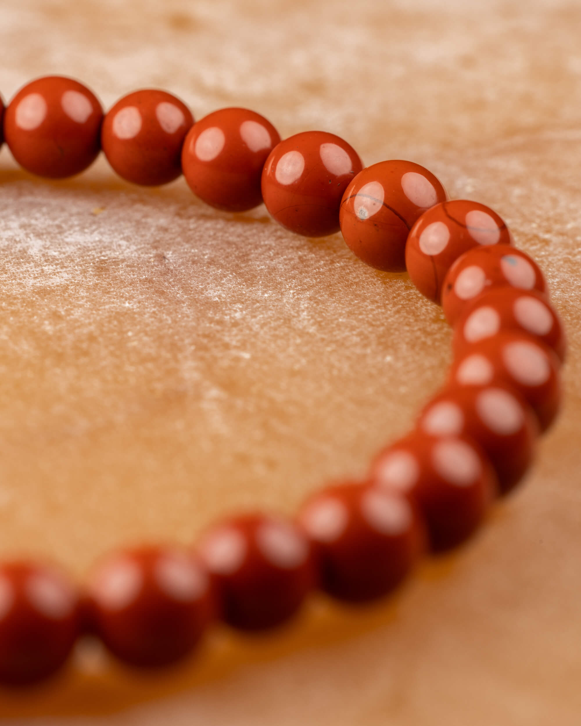 Pulsera de Jaspe Rojo curvada en ángulo diagonal sobre superficie clara