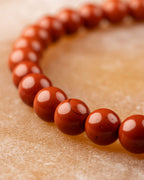 Pulsera de Jaspe Rojo curvada mostrando el degradado de tono en cada cuenta
