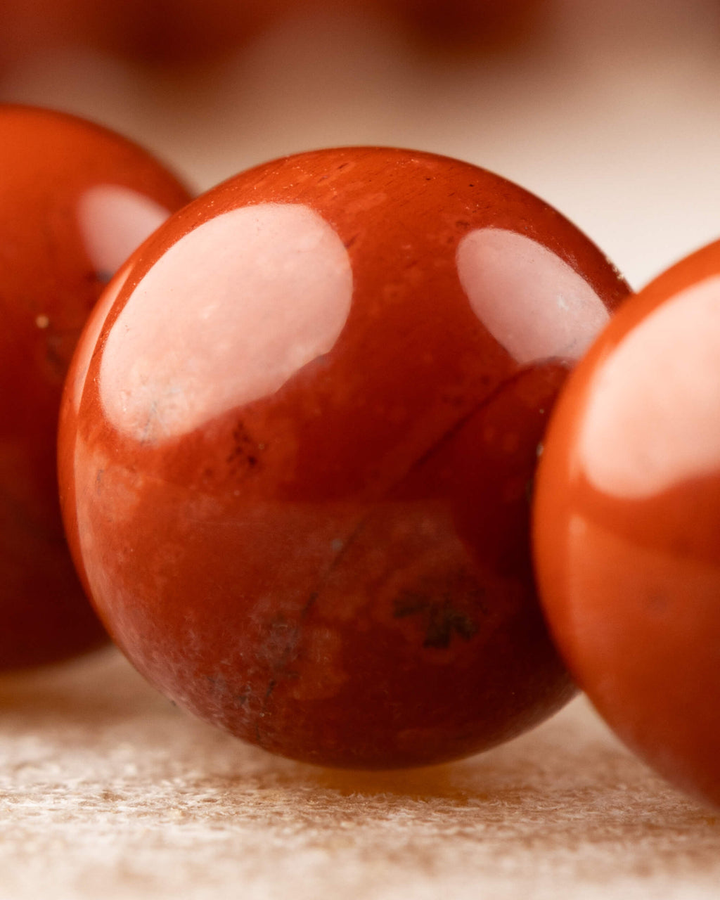 Detalle macro de una cuenta de Jaspe Rojo mostrando su superficie pulida y opaca