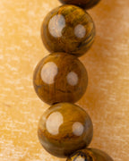 Detalle macro vertical de cuentas de Pietersita amarilla con brillos y vetas cafés
