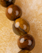 Detalle macro vertical de cuentas de Pietersita amarilla con vetas cafés y brillos