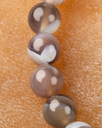 Detalle macro vertical de cuentas de Ágata Botsuana en tonos gris y beige