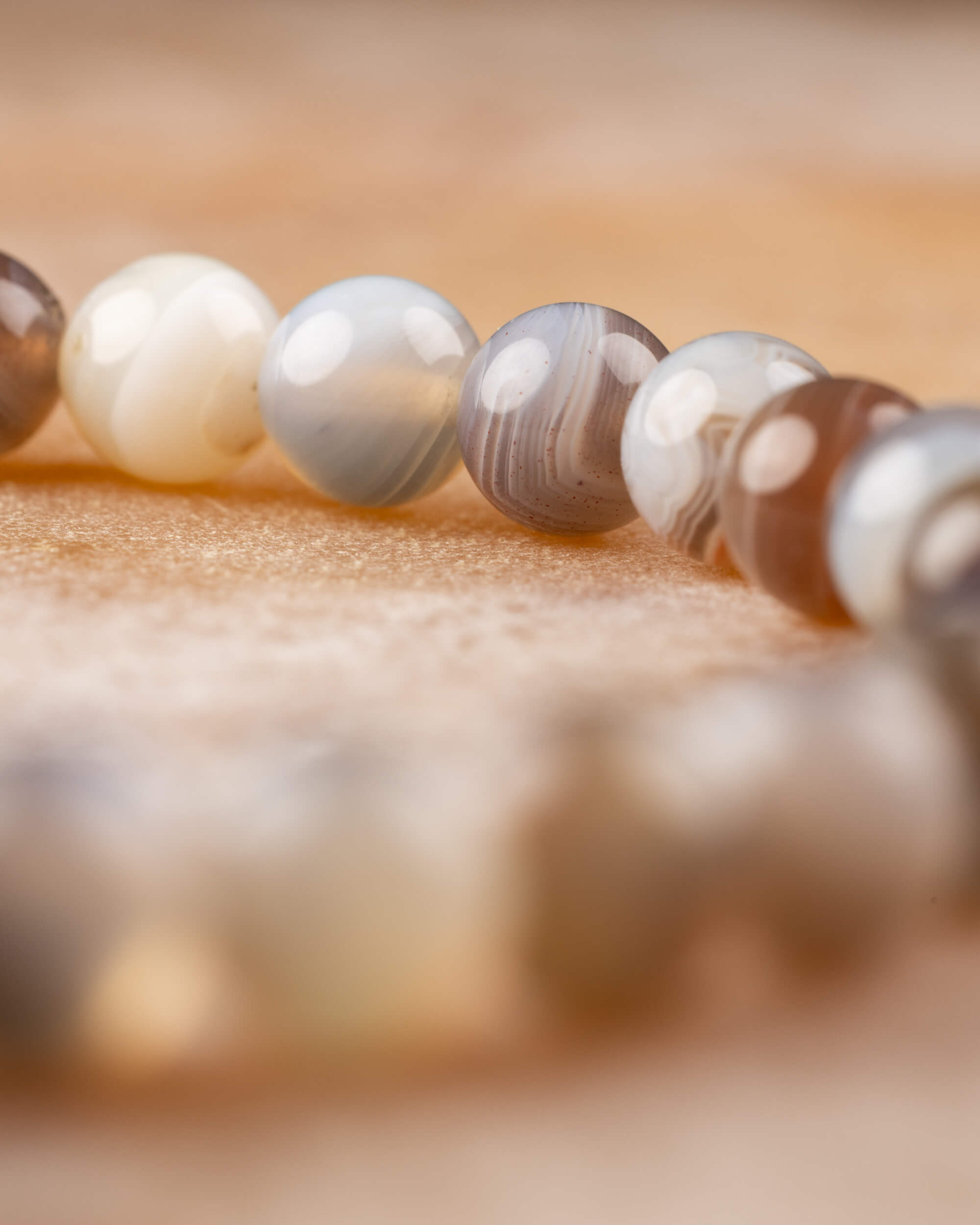 Detalle macro de cuentas de Ágata Botsuana en fila, tonos crema y gris