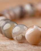 Detalle macro de las cuentas bandeadas de Ágata Botsuana, tonos gris y crema