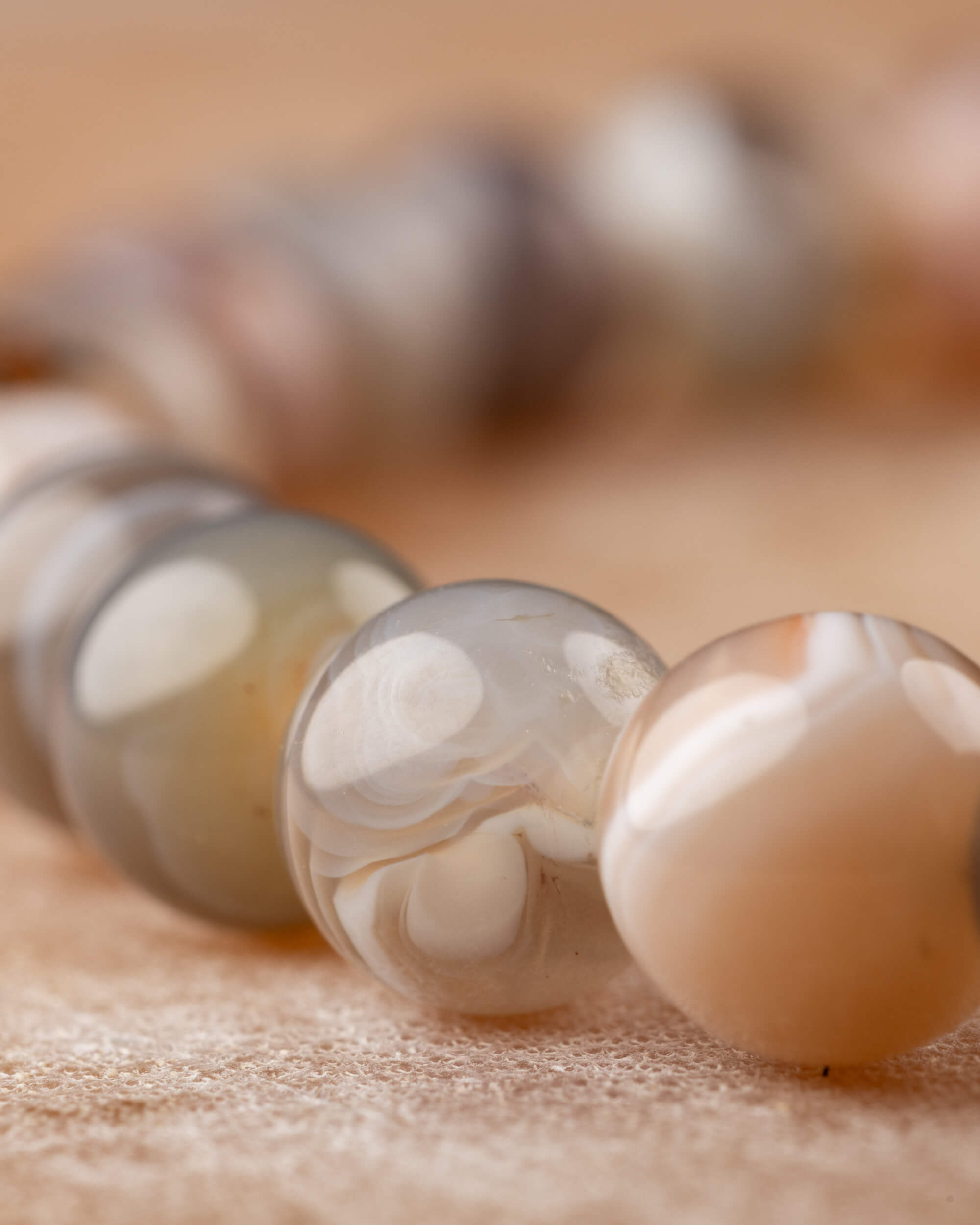 Detalle macro de las cuentas bandeadas de Ágata Botsuana, tonos gris y crema