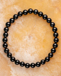Pulsera de Turmalina Negra de 6 mm, pieza completa en círculo sobre superficie clara
