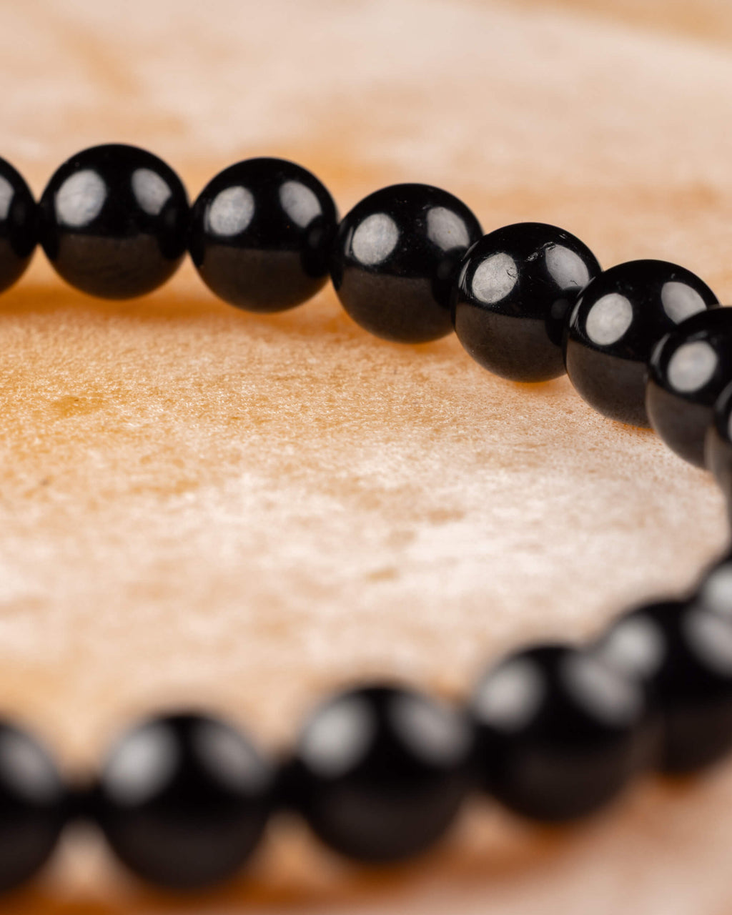 Pulsera de Turmalina Negra en ángulo, cuentas alineadas sobre madera