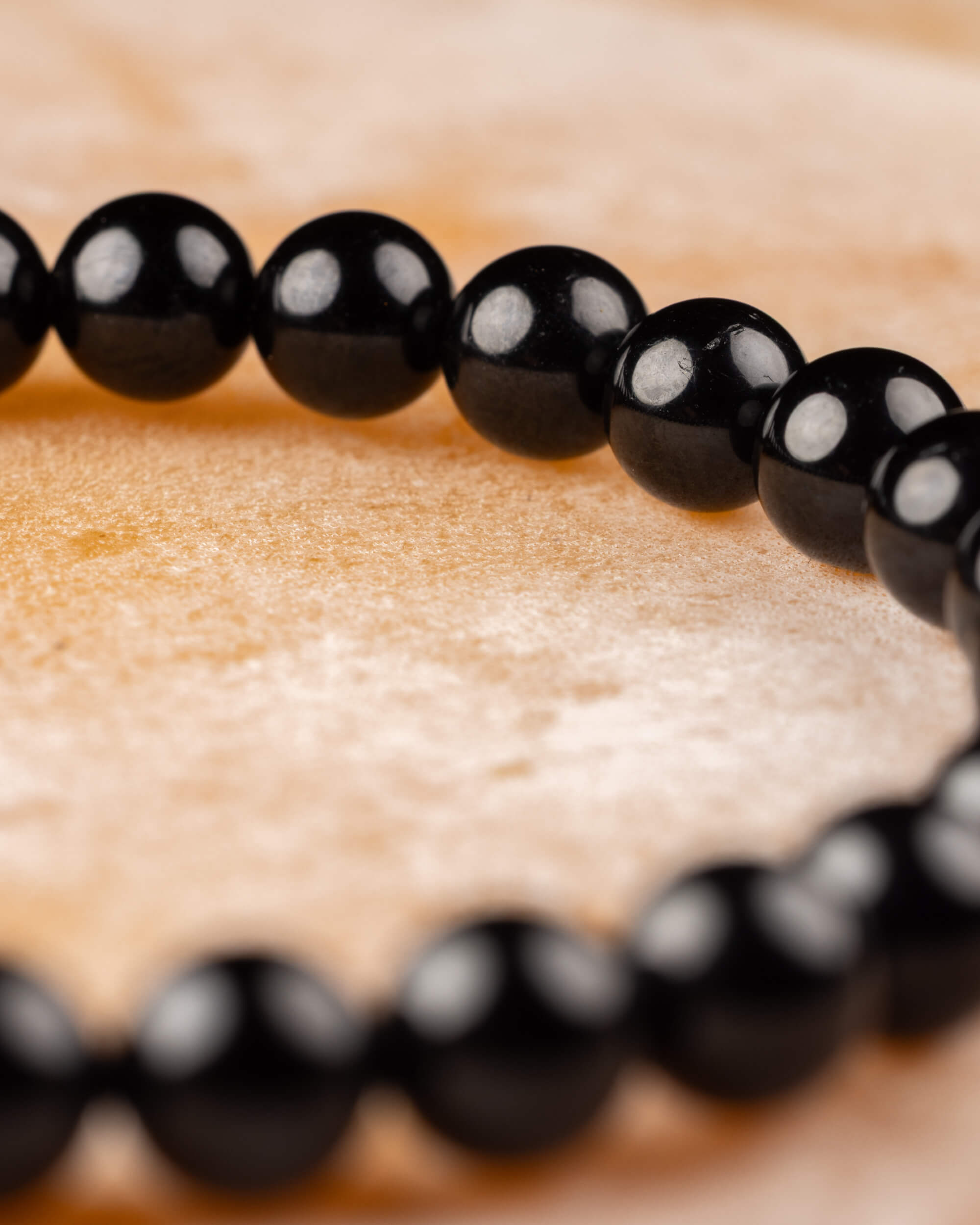 Pulsera de Turmalina Negra en ángulo, cuentas alineadas sobre madera